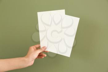 Female hand with blank invitation cards on color background�