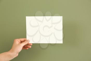 Female hand with blank invitation card on color background�