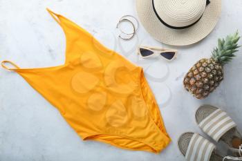 Female swimming suit, hat, pineapple and beach shoes on light background. Travel concept�
