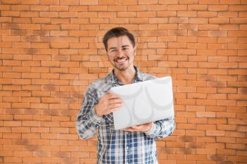 Male programmer with laptop on brick background�