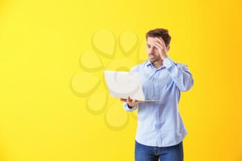 Shocked male programmer with laptop on color background�