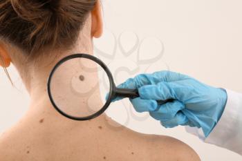 Dermatologist examining moles of patient on light background�