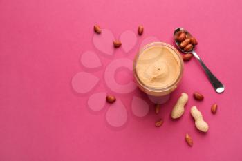 Jar with peanut butter on color background�