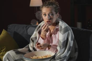 Beautiful young woman eating unhealthy food at night�