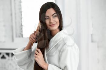 Beautiful young woman brushing her healthy long hair at home�
