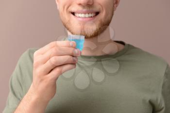Young man with cup of mouthwash on color background�