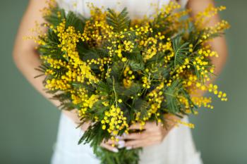 Woman with bouquet of mimosa flowers, closeup�
