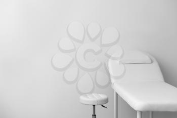 Treatment couch with stool on light background�