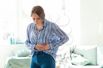Young woman suffering from stomachache at home�