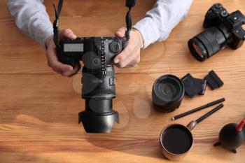 Professional photographer with modern camera and accessories at table�