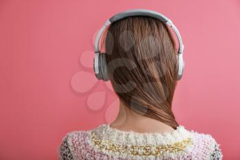 Young woman with headphones listening to music on color background�
