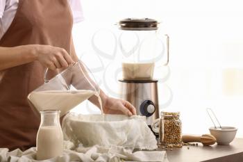 Woman making soy milk in kitchen�