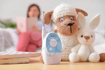 Modern baby monitor with toys on table in room�