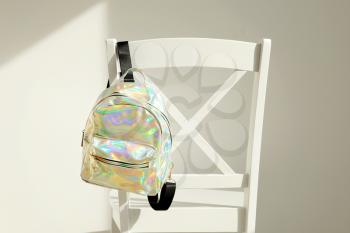 Stylish backpack from iridescent material on back of chair�