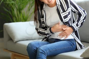 Young woman suffering from abdominal pain at home�