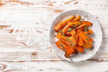Plate with tasty cooked carrot on wooden table�