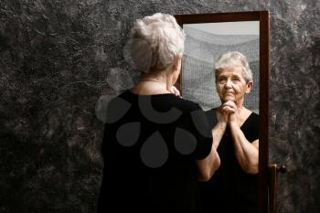 Senior woman looking in mirror�