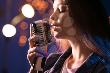 Beautiful female singer with microphone on stage�