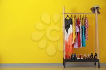 Rack with stylish clothes near color wall�