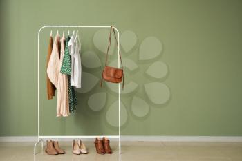 Rack with stylish clothes near color wall�