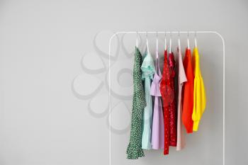 Rack with stylish clothes on grey background�