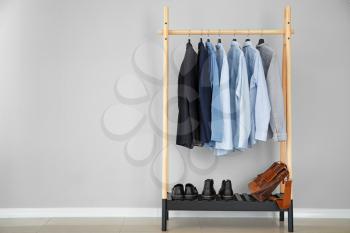 Rack with stylish male clothes near light wall�