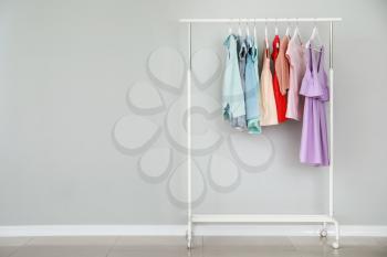 Rack with stylish children's clothes near light wall�