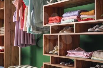 Wooden rack with children's clothes in dressing room�