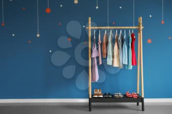Rack with children's clothes near color wall�