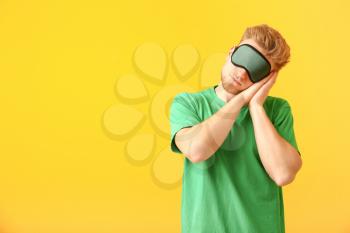 Sleepy man with mask on color background�