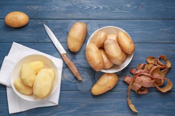 Raw potatoes with knife on wooden background�