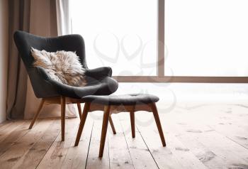 Comfortable armchair and footstool near window in flat�