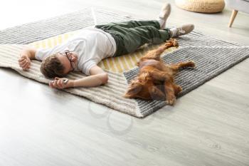 Teenage boy with cute dog lying on carpet at home�