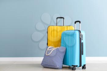 Packed suitcases and beach bag near color wall�