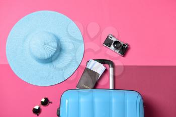Suitcase, hat, photo camera and documents on color background. Travel concept�