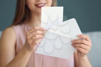 Young woman opening envelope with invitation at home, closeup�