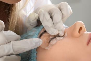 Young woman undergoing procedure of eyelashes lamination in beauty salon, closeup�