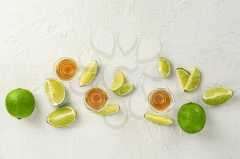Composition with shots of tequila and lime on white background�