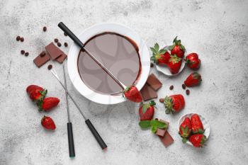 Bowl with tasty chocolate fondue and strawberry on table�