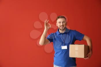 Handsome delivery man showing OK on color background�