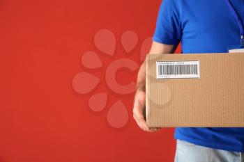Delivery man with box on color background, closeup�