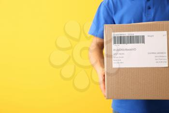 Delivery man with box on color background, closeup�