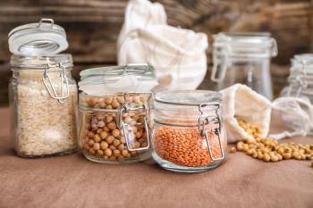 Glass jars with different food on kitchen table�