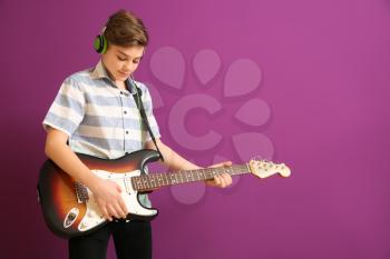 Teenage boy playing guitar against color background�