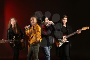Band of teenage musicians on dark background�