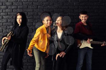 Band of teenage musicians playing against dark wall�