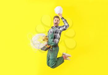 Jumping male electrician on color background�