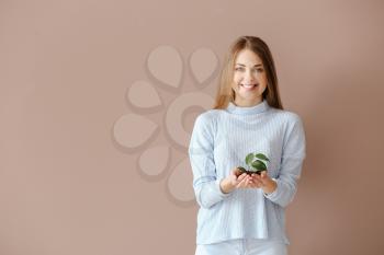 Woman with young plant on color background�