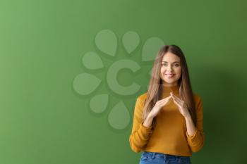 Young deaf mute woman using sign language on color background�