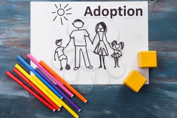 Drawing of family, felt-pens and word ADOPTION on wooden background�